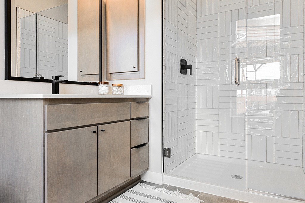 A bathroom with a white tiled shower and a wooden vanity.