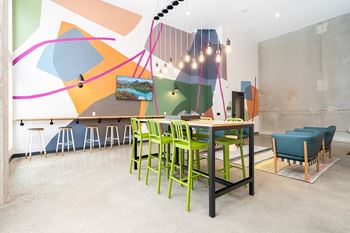 A room with a table and chairs and a wall with a painting on it.