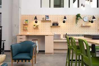 A room with a desk, chairs and a pegboard on the wall.