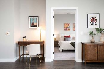 A room with a desk and a bed in the background.