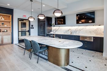 A modern kitchen with a marble countertop and a round table with four chairs.