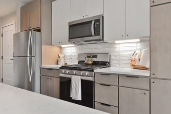A modern kitchen with a stainless steel refrigerator and a microwave oven mounted above the stove.