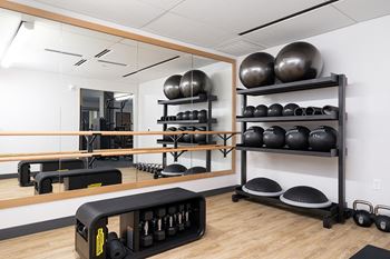 A gym with a mirror, weights, and exercise balls.