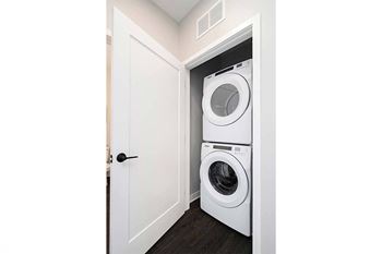 Two washing machines are stacked in a small laundry room.