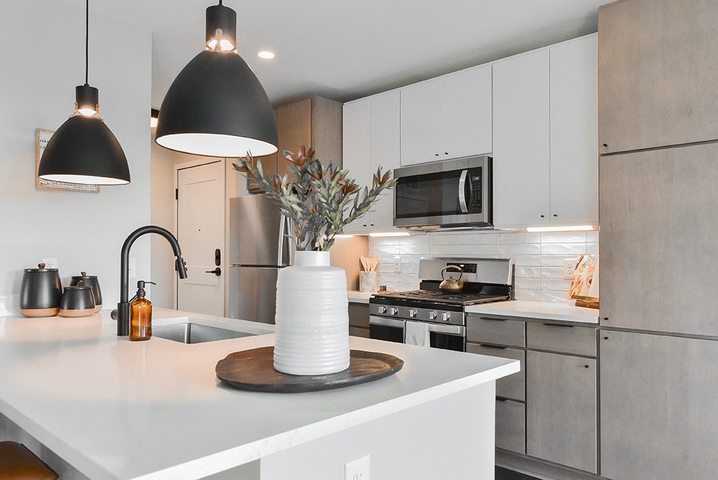 A modern kitchen with a white countertop and a microwave above it.