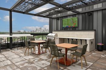 A patio with a table and chairs and a TV showing a football game.