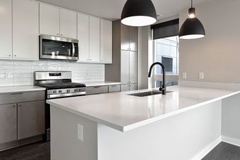 A modern kitchen with a white countertop and stainless steel appliances.