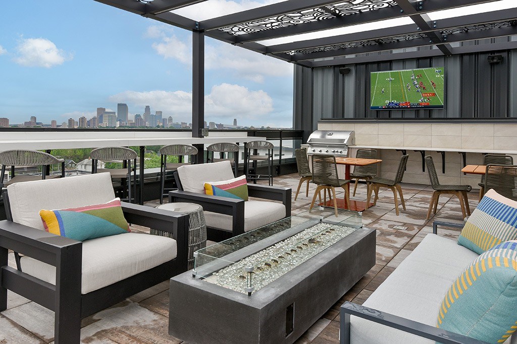 A patio with a table, chairs, and a TV showing a football game.