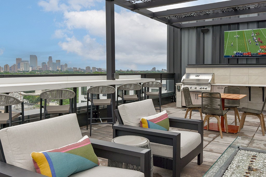 A patio with a couch and chairs overlooking a city skyline.