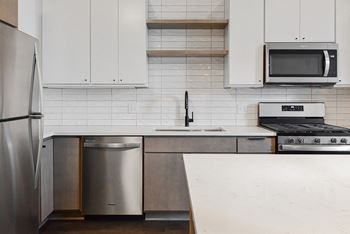 A kitchen with a stainless steel refrigerator, microwave, and oven.