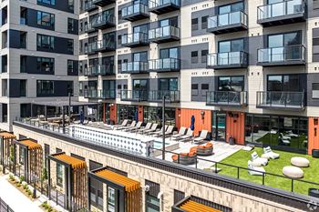 A modern apartment complex with a pool and lounge area.