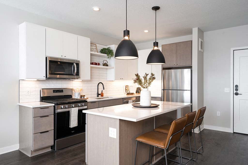 A modern kitchen with a white countertop and brown chairs.