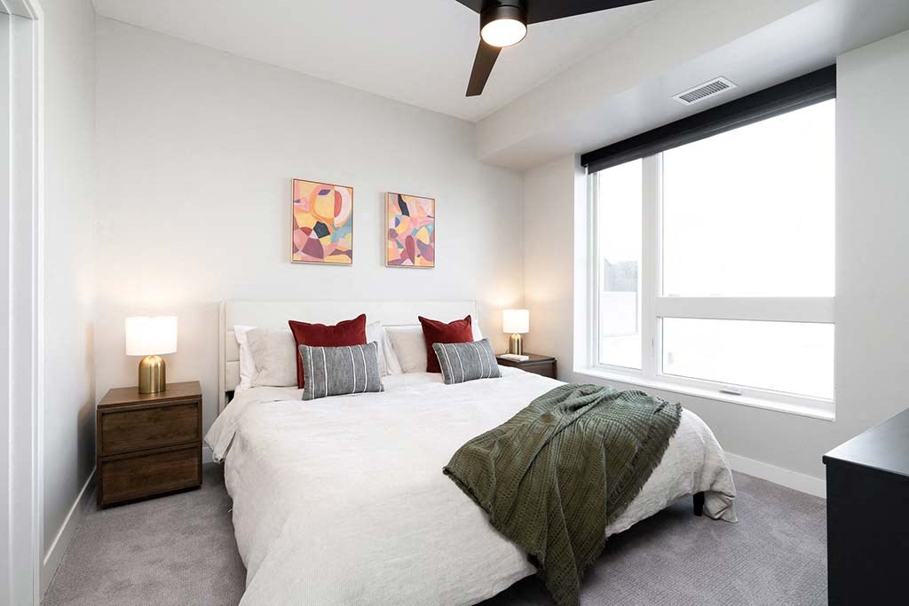 A bedroom with a bed, nightstands, and a ceiling fan.