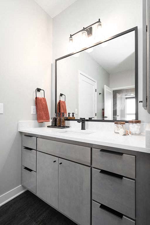 A bathroom with a white counter top and a large mirror.