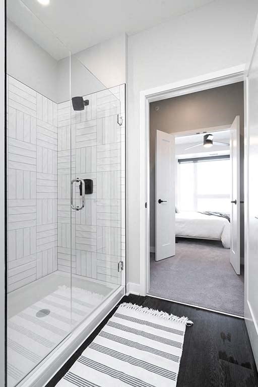 A bathroom with a walk-in shower and a bedroom in the background.