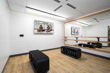 A black sofa in a white room with wooden floors and a painting on the wall.