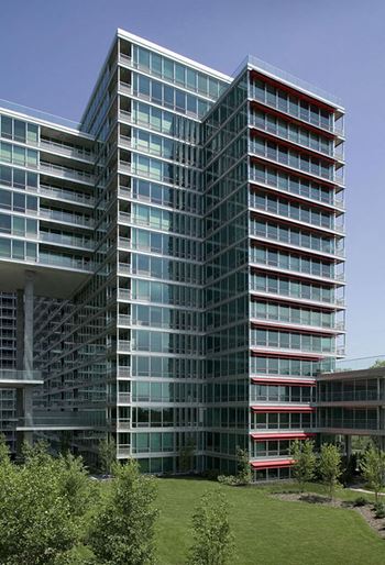 A modern glass building with red accents on the balconies.