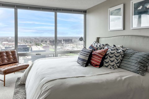A bedroom with a large bed and a view of the city at our apartments in North Chicago.