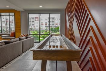 A shiny pool table is in the middle of a room with a couch and a window.