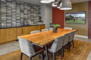 A modern dining room with a wooden table and grey chairs.
