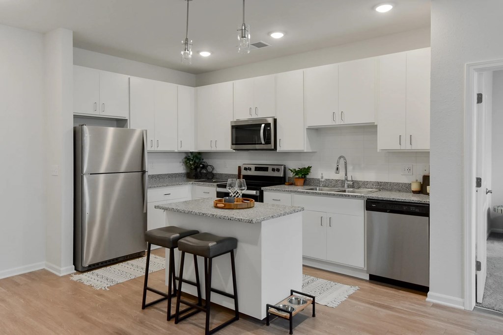 A kitchen with white cabinets and a stainless steel refrigerator.
