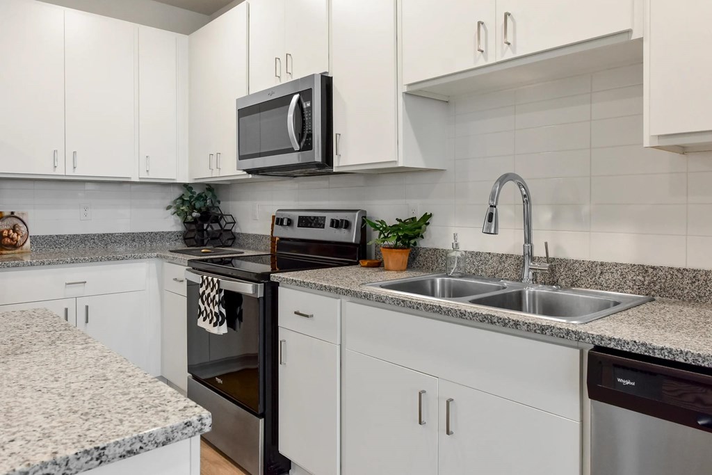 A kitchen with white cabinets and a granite countertop.