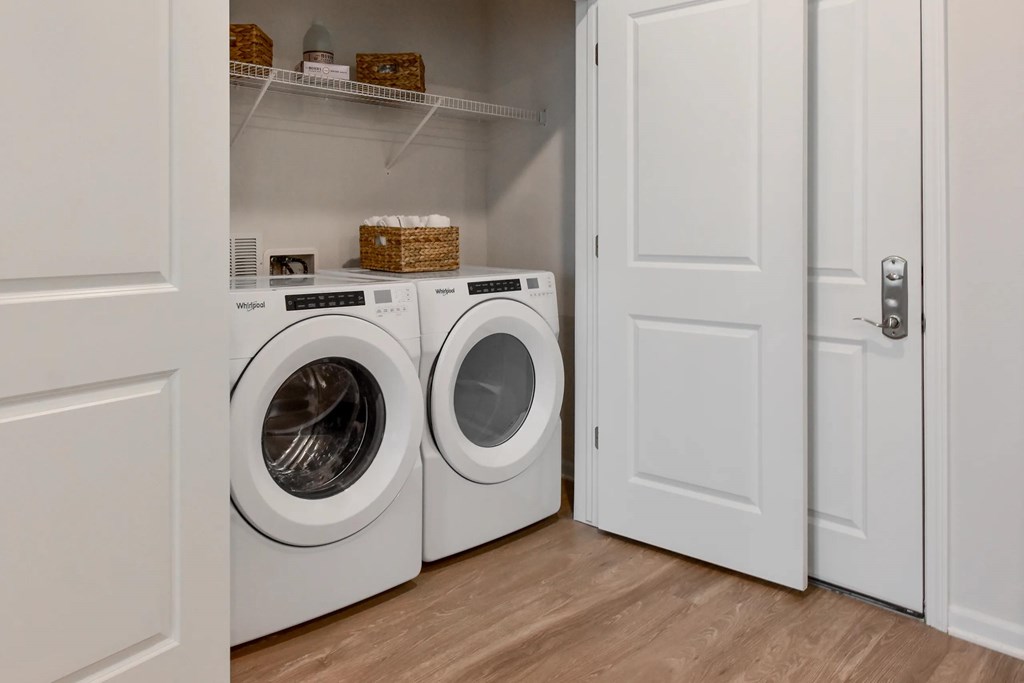 Two washing machines are in a white laundry room.