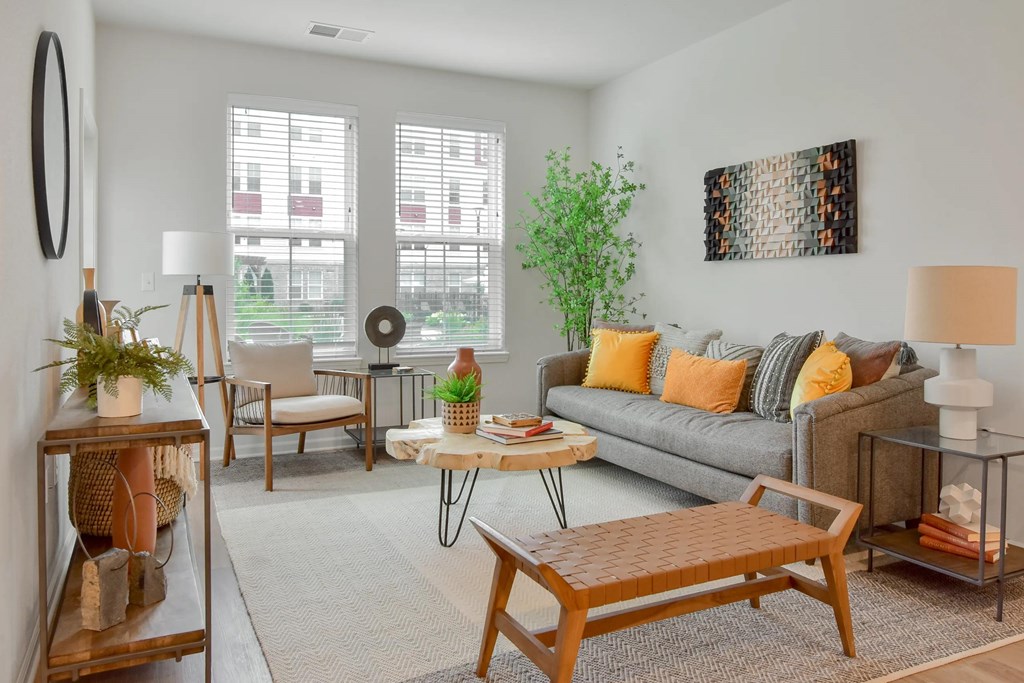 A living room with a grey couch, a wooden coffee table, and a large window.
