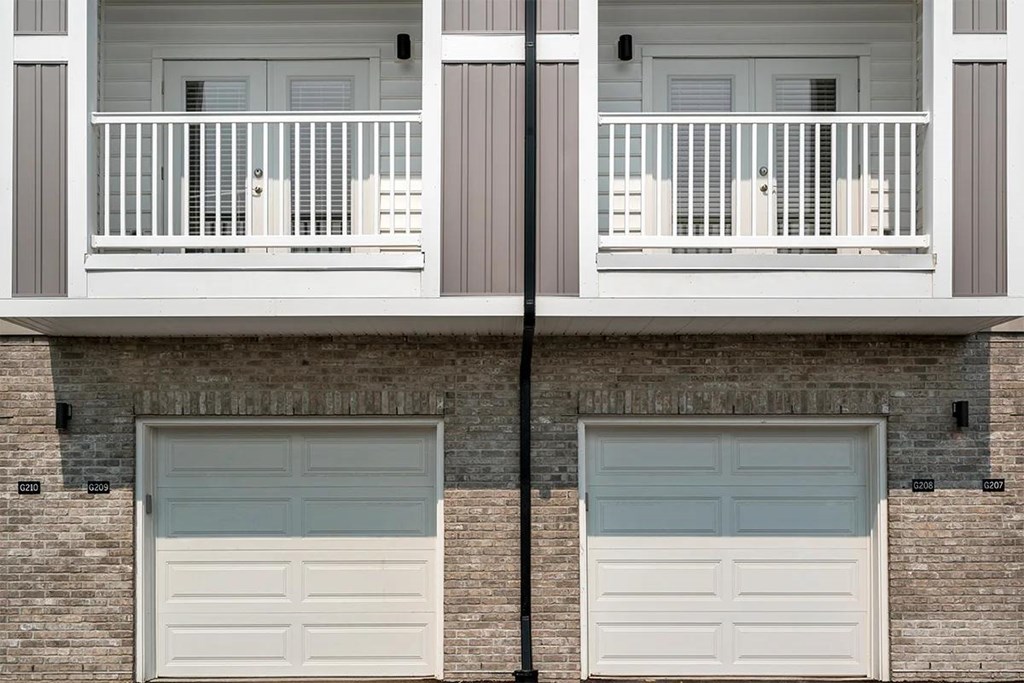 A building with two garage doors and a balcony.