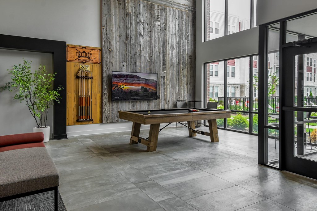 A room with a wooden table and a painting of a sunset on the wall.