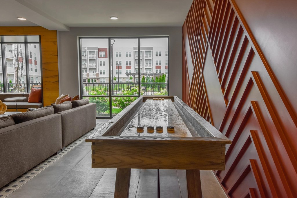 A shiny pool table is in the middle of a room with a couch and a window.