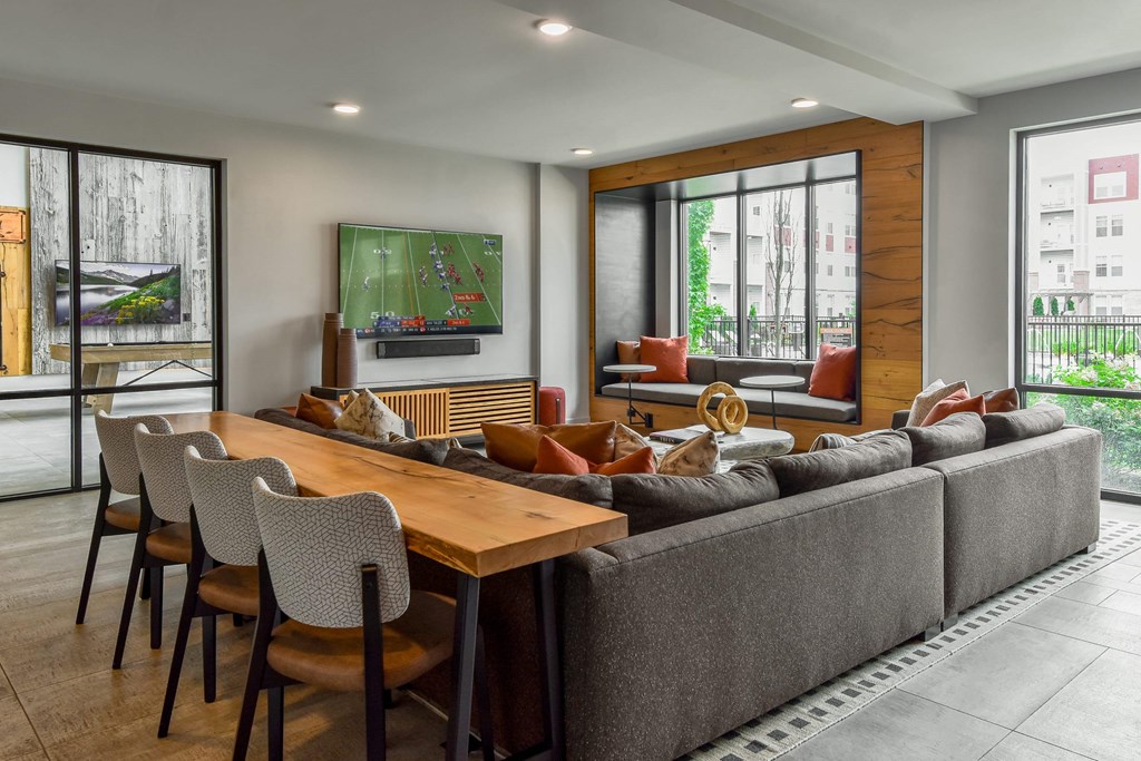 A modern living room with a long wooden table and grey couch.