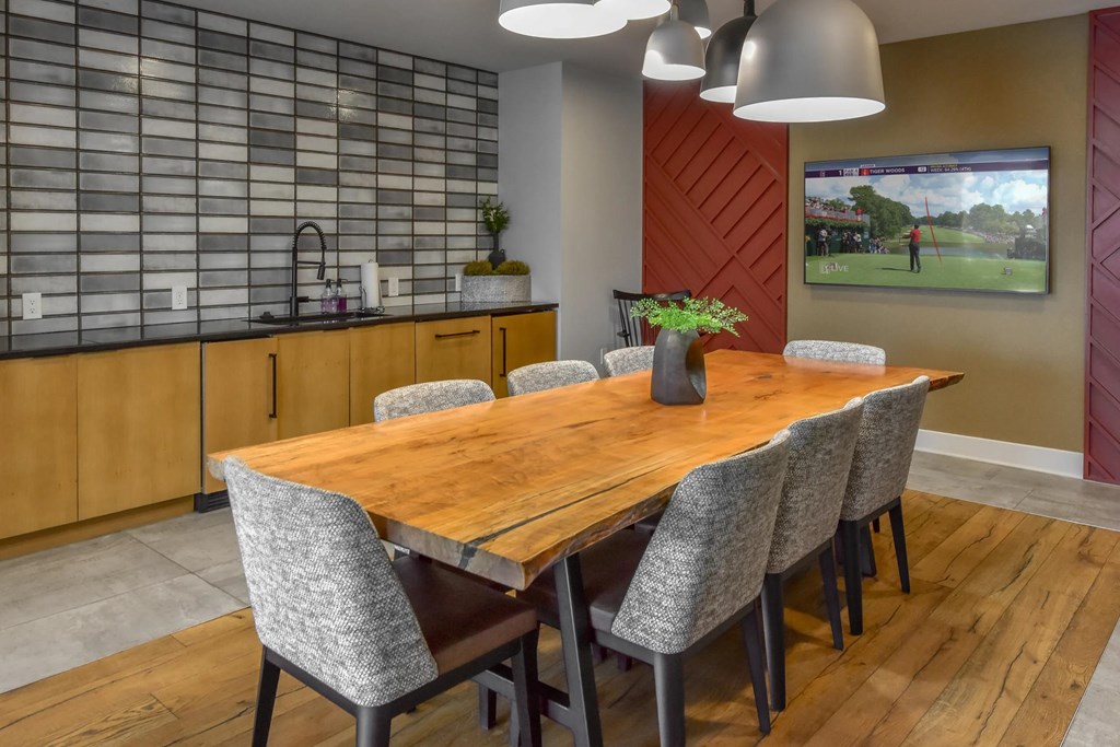 A modern dining room with a wooden table and grey chairs.