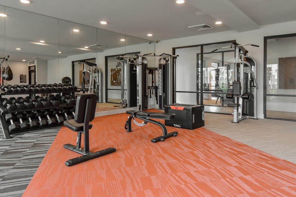 A gym with orange flooring and various exercise equipment.