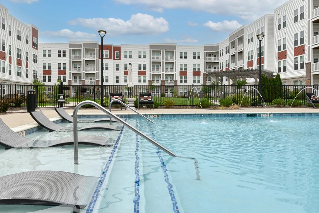 Resort-style swimming pool with lounge chairs at The View on Collins apartments for rent in Lansing, MI