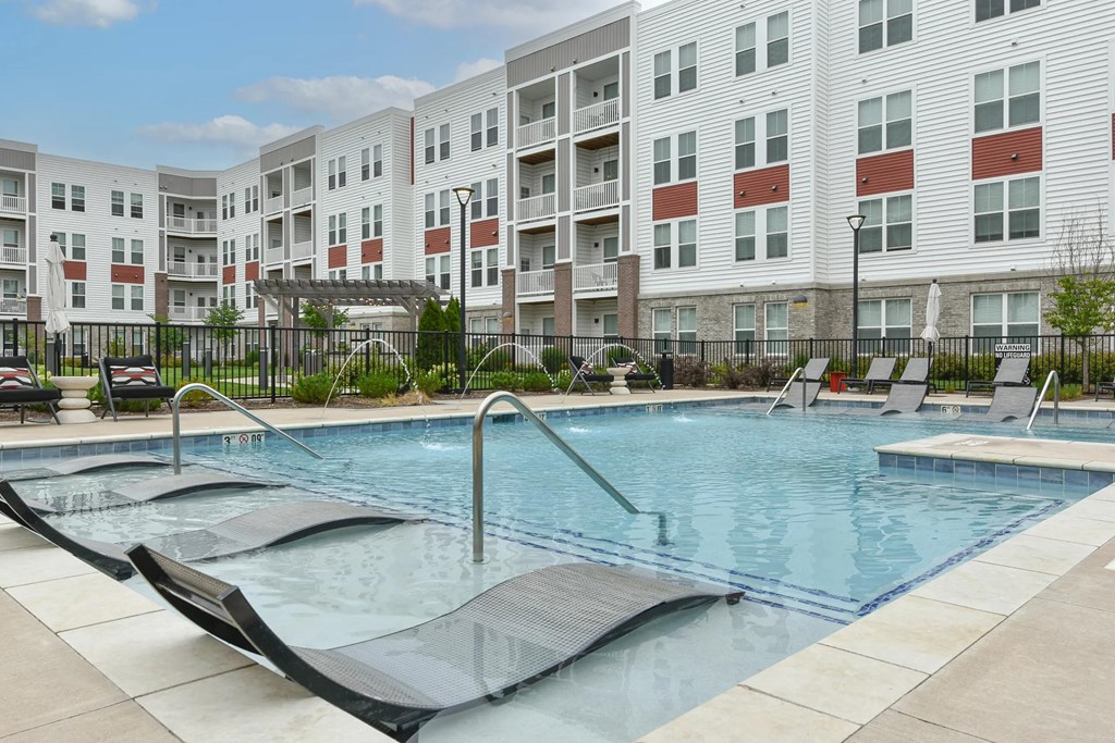 Pool with lounge chairs and safety rails at The View on Collins luxury apartments in Lansing, MI