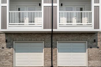 A building with two garage doors and a balcony.