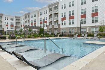 Pool with lounge chairs and safety rails at The View on Collins luxury apartments in Lansing, MI