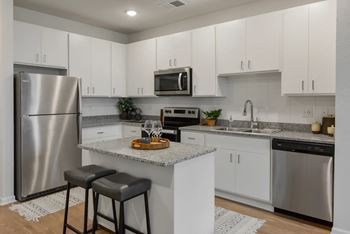 A kitchen with a refrigerator, microwave, and bar stools.