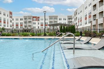 A swimming pool with a diving board in front of apartment buildings.