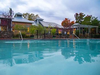A pool in front of a house with a fence around it.
