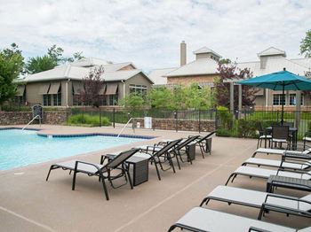 A poolside area with sun loungers and a building in the background.