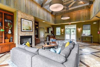 A large grey couch sits in the middle of a spacious room with a fireplace.