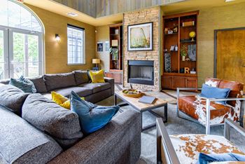 A living room with a grey couch and a fireplace.