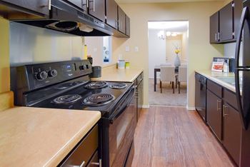 A kitchen with a black stove top oven and black cabinets.
