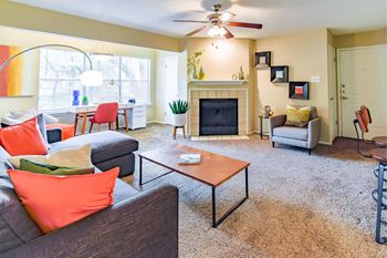 A living room with a grey couch, orange pillows, a coffee table, and a fireplace.