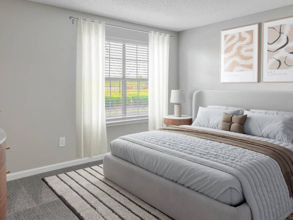 A bedroom with a large bed and a window with blinds.