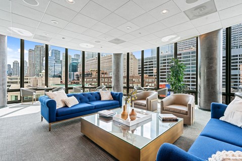 A living room with blue couches and a glass coffee table.