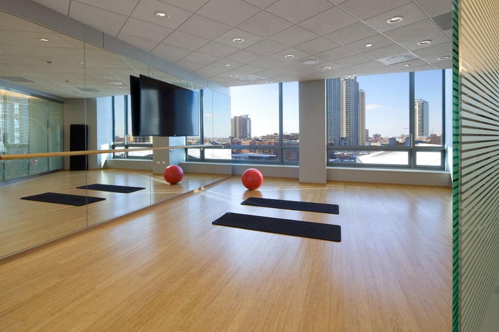 A yoga studio with wooden floors and mirrors on the wall.