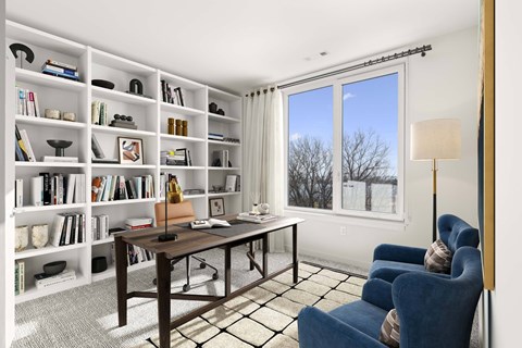 A room with a desk, chairs, and bookshelves.